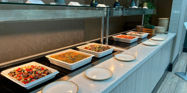 Multiple serving plates of professionally prepared hot buffet foods, sat of hot counter, ready for event attendees to serve themselves.