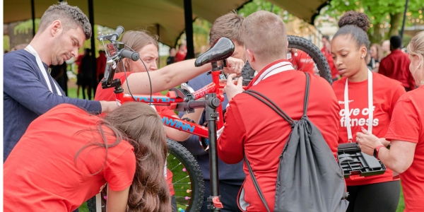 Group of five people - men and women, dressed in red t-shirts and building a bike