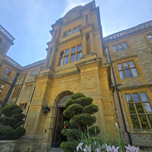 the entrance to a large stone building with flowers in front of it